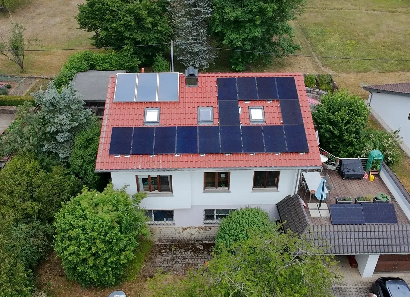 Luftaufnahme eines Wohnhauses mit Photovoltaikanlage auf einem roten Satteldach