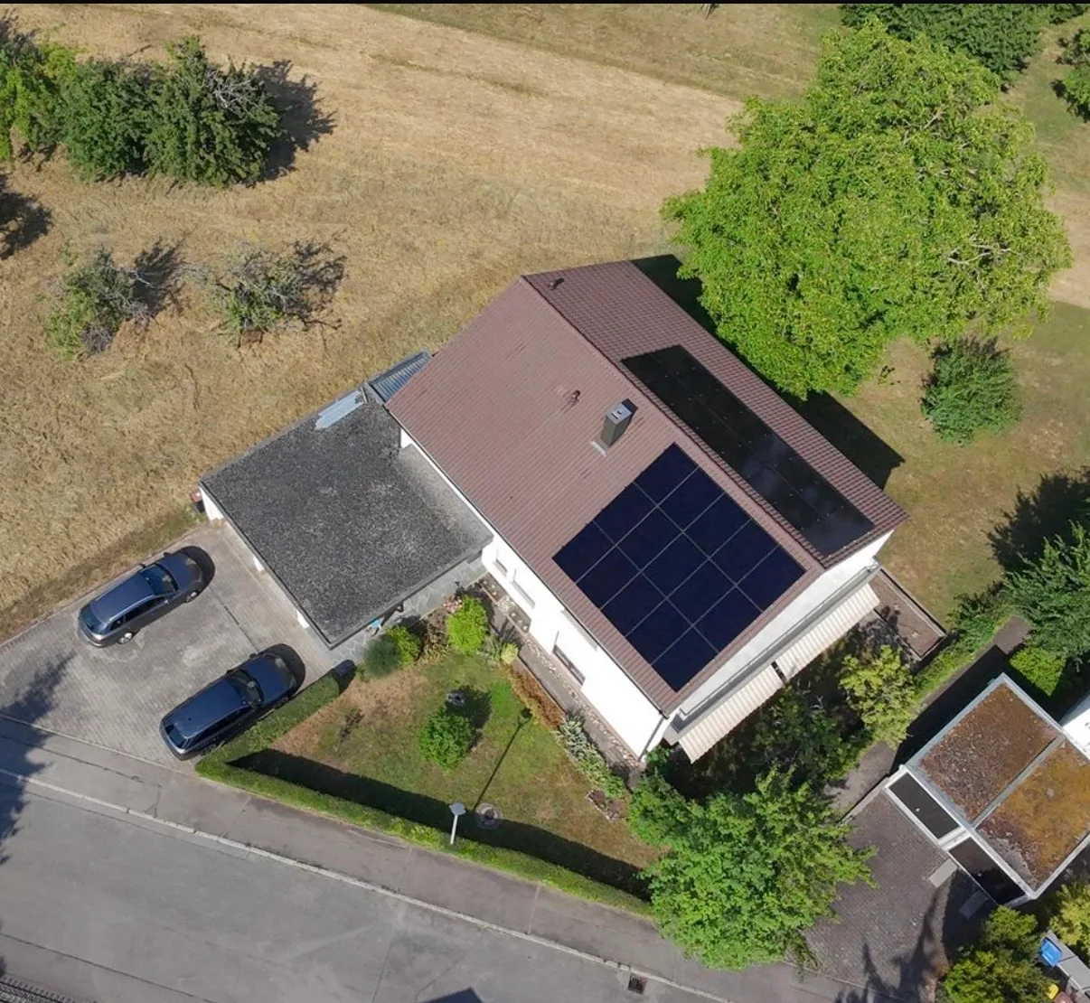 Luftaufnahme eines Mehrfamilienhauses mit einer PV-Anlage auf dem Satteldach.
