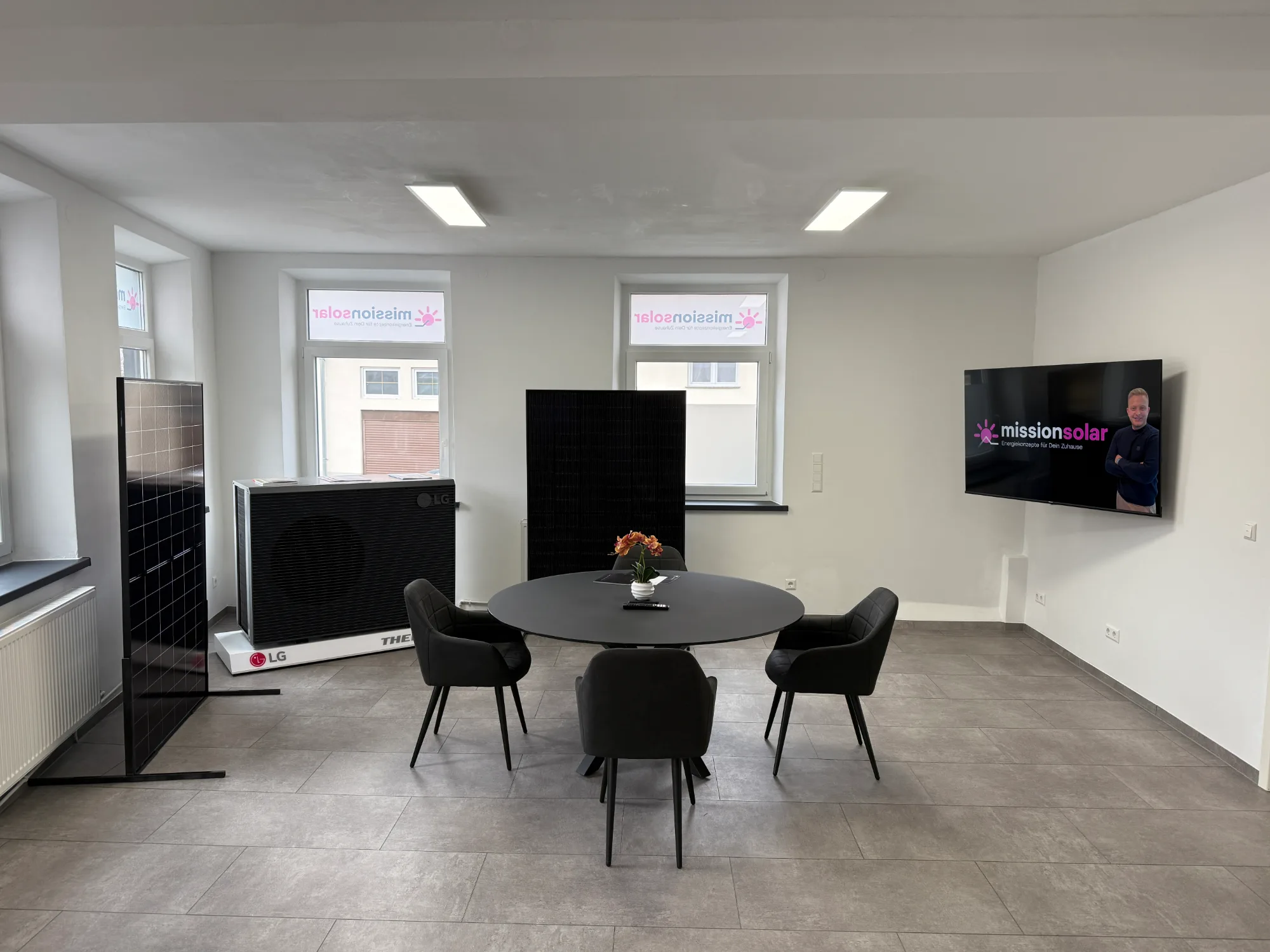 Showroom von Mission Solar mit Beratungstisch, ausgestellten Solarmodulen und einer LG-Wärmepumpe.