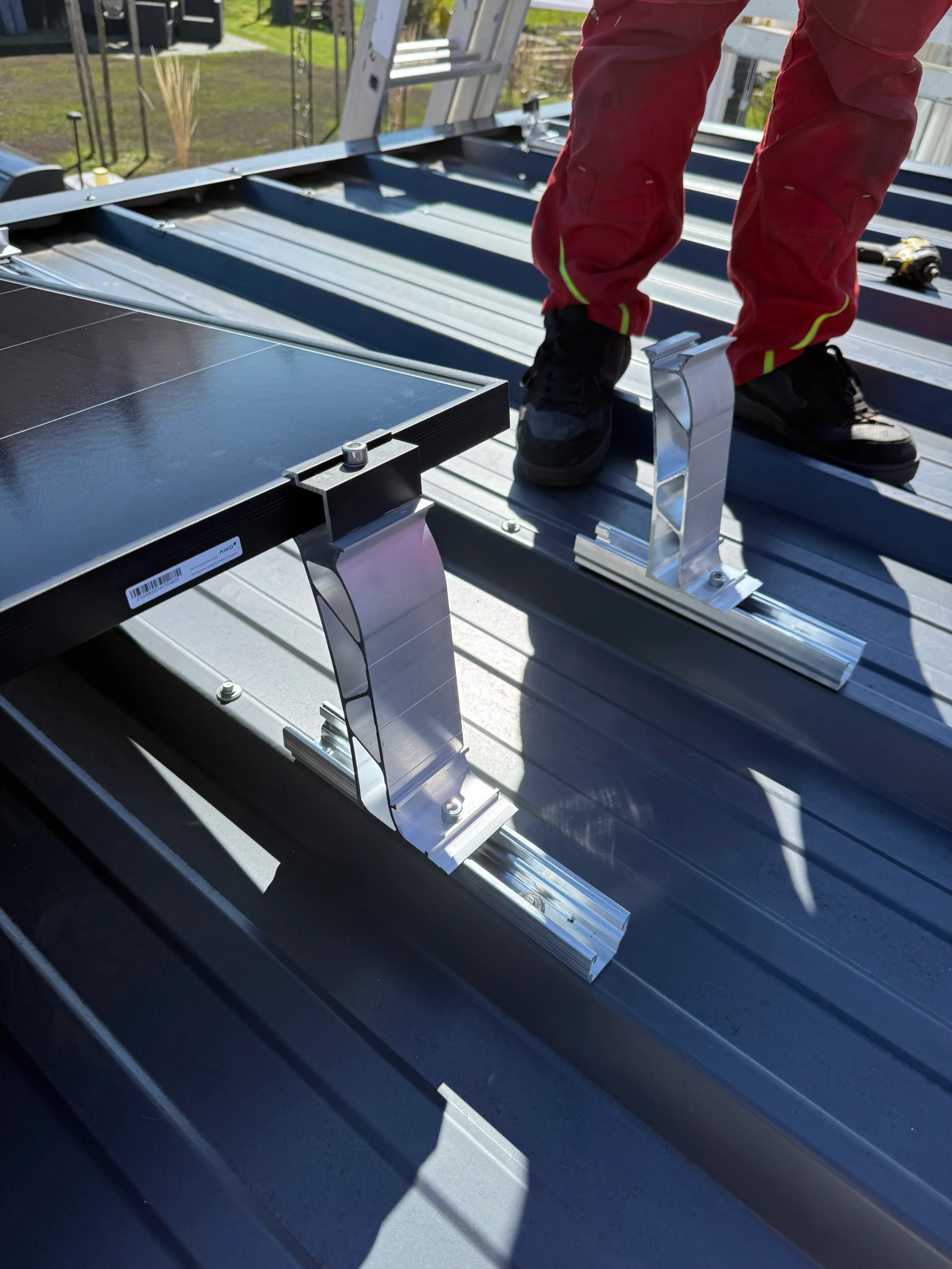Monteure verlegen Photovoltaikmodule auf einem Blechdach