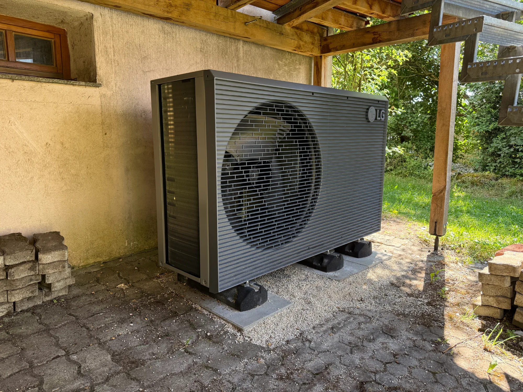 Außeneinheit einer Wärmepumpe unter einem Vordach an einer Hauswand