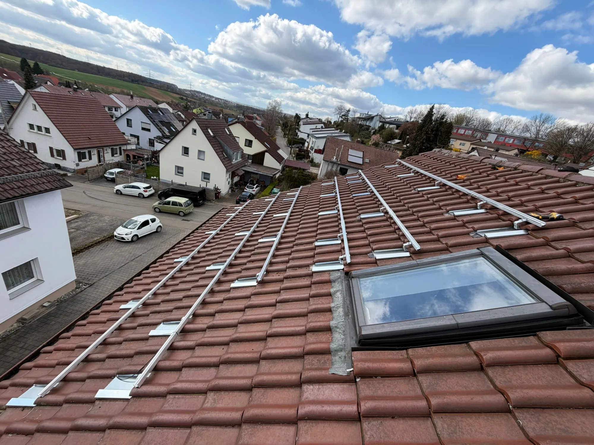Montageschienen für eine Photovoltaikanlage auf einem rot eingedeckten Ziegeldach.